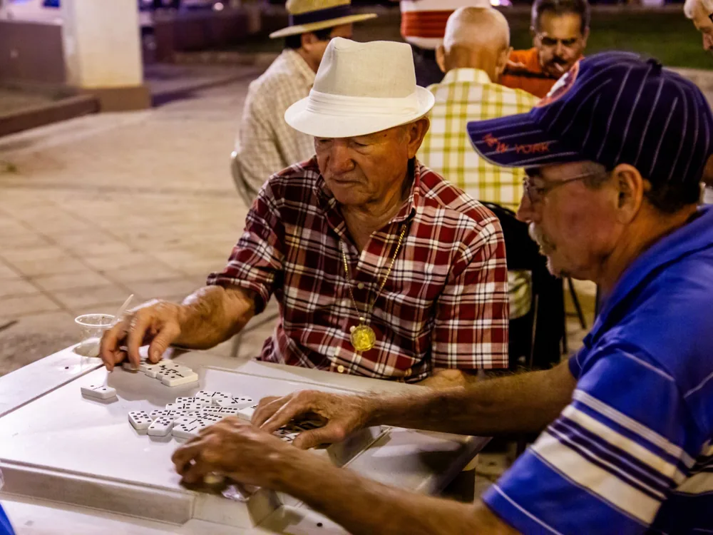 Hombres mayores jugando dominó en una plaza de noche